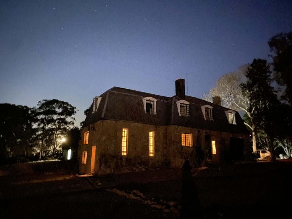 Foto da Casa de Pedra com as luzes acesas após o anoitecer